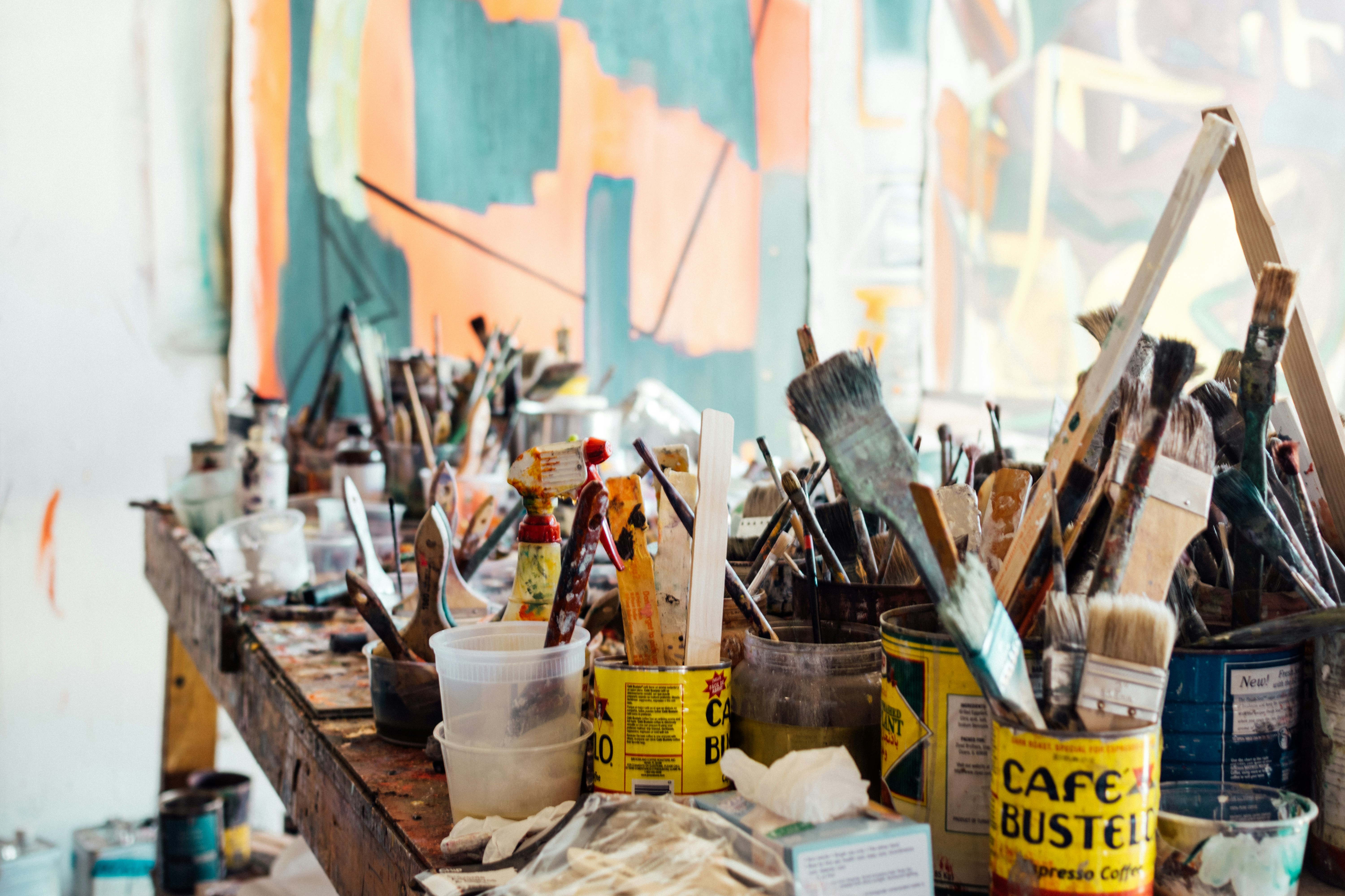 assorted paint brushes in cans on a wooden table - Unsplash by Khara Woods